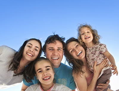Family smiling with a blue sky background at Cascade Dental in Medford, OR