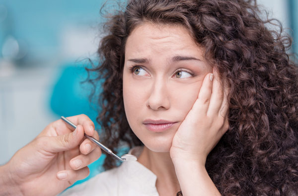 Woman holding cheek due to toothache at Cascade Dental in Medford, OR