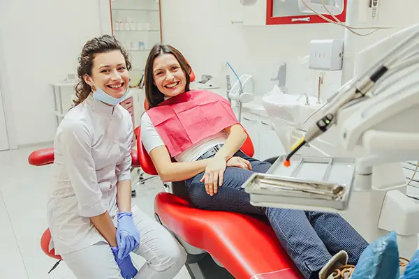 A dentist smiling brightly with her seated patient at  Cascade Dental in Medford, OR
