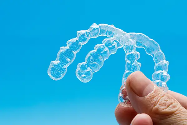 Close-up of a hand holding upper and lower Invisalign clear aligner trays at Cascade Dental in Medford, OR